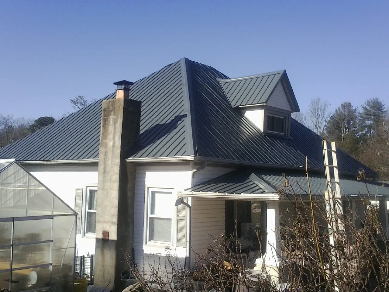 Dark blue standing seam metal roof on a white farmhouse with dormer — Slate & Tile Roof Repair by Roofing Brothers in Patoka