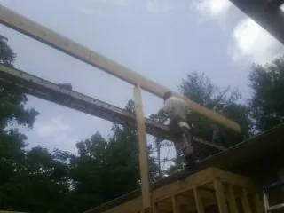 Carpenter setting a ridge beam over a new addition frame — Ice Dam Removal by Roofing Brothers in Patoka