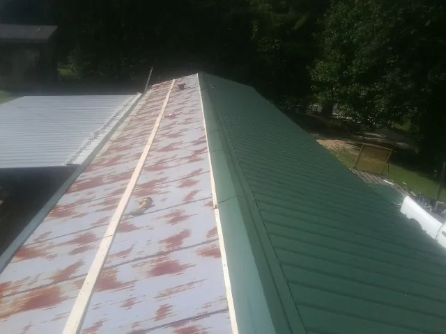Old rusted panels beside newly installed green metal roofing — Wind Damage Roof Repair by Roofing Brothers in Patoka