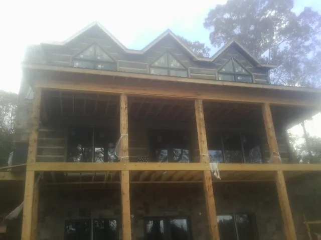 Dormers and porch framing on a large log home under construction — Roof Coating work by our crew in Patoka