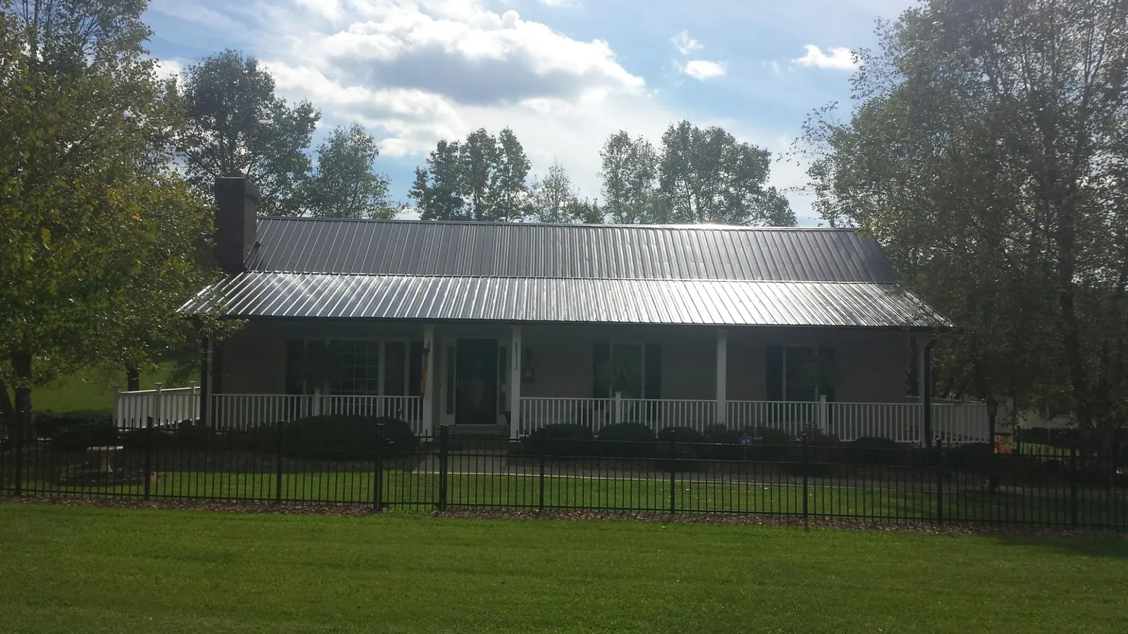 Gray metal roof on a brick ranch with a full width front porch — Gutter Guard Installation work by our crew in Patoka