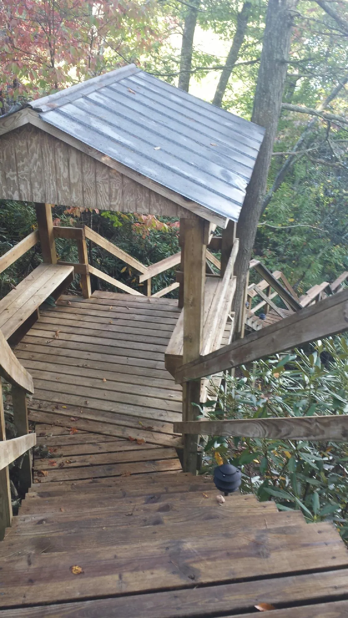 Metal roofed shelter over wooden steps on a wooded walkway — Skylight Repair & Installation work by our crew in Patoka