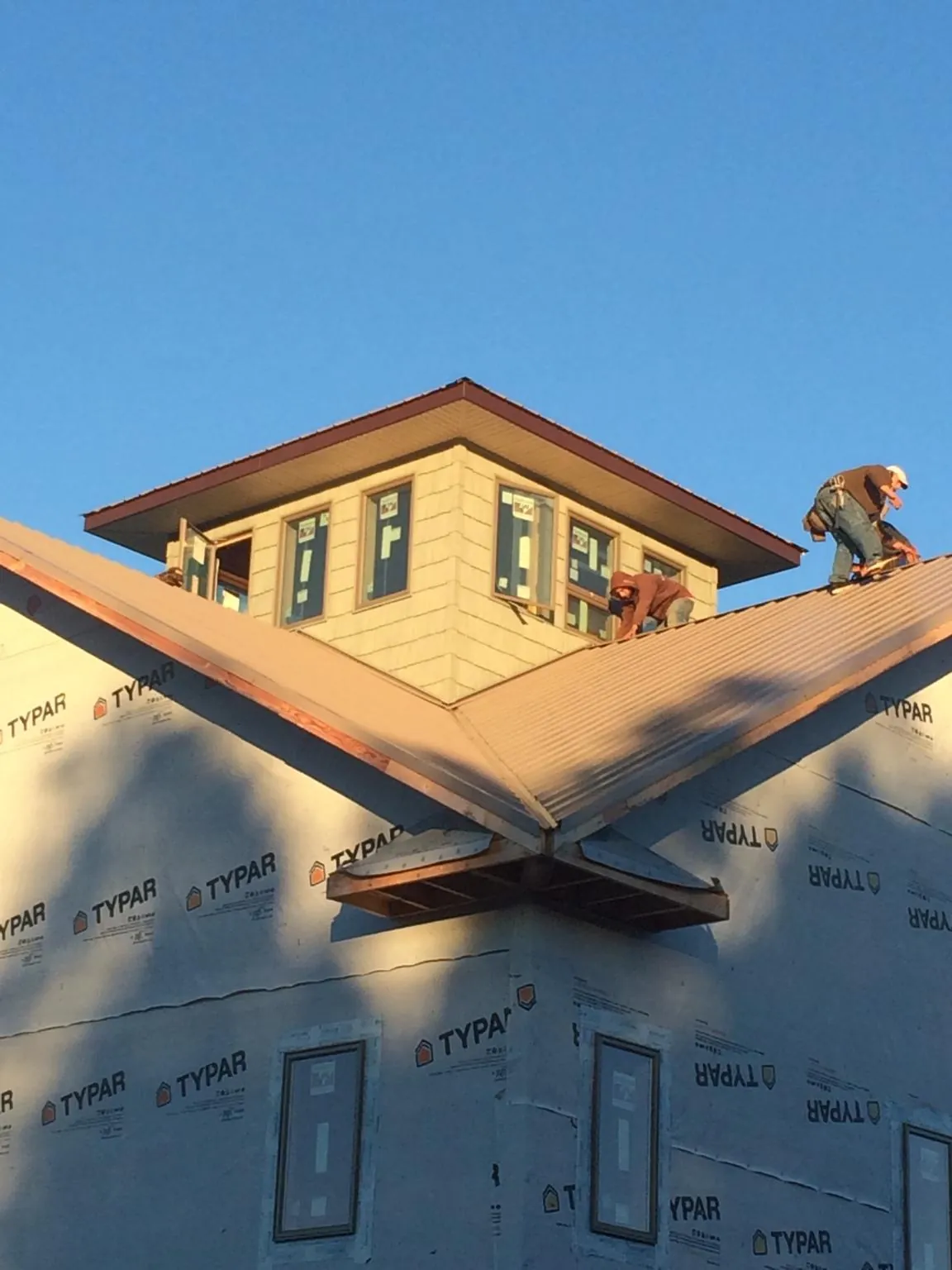Roofers working around a rooftop cupola on a new metal roof at sunset — Roof Waterproofing in Patoka by Roofing Brothers